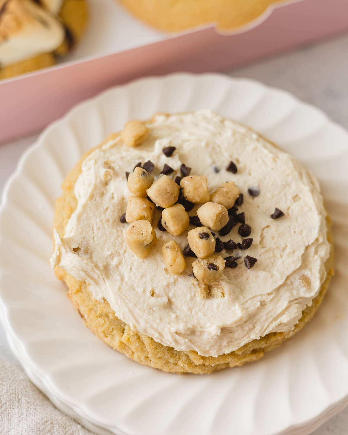 A Chocolate Chip Cookie Dough Crumbl Cookie on a small stack of white plates.