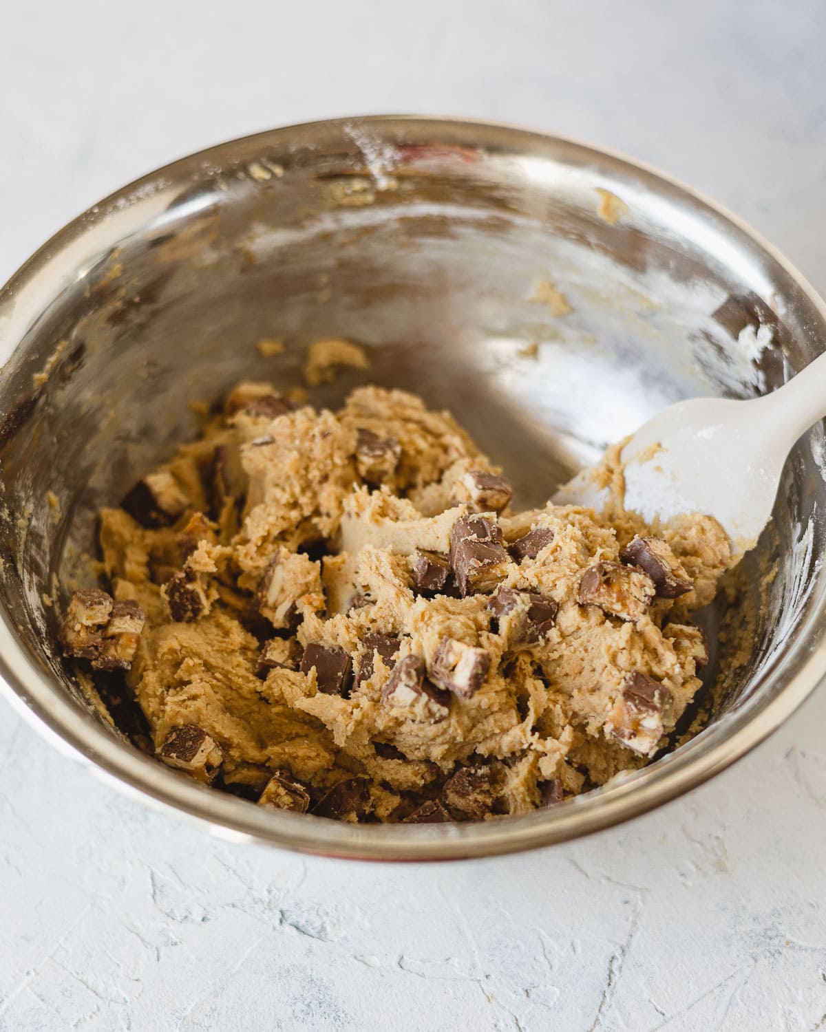 A metal bowl with Peanut Butter Snickers cookie dough.