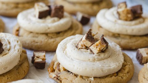Peanut butter cookies frosted with caramel buttercream and chopped Snickers bars.