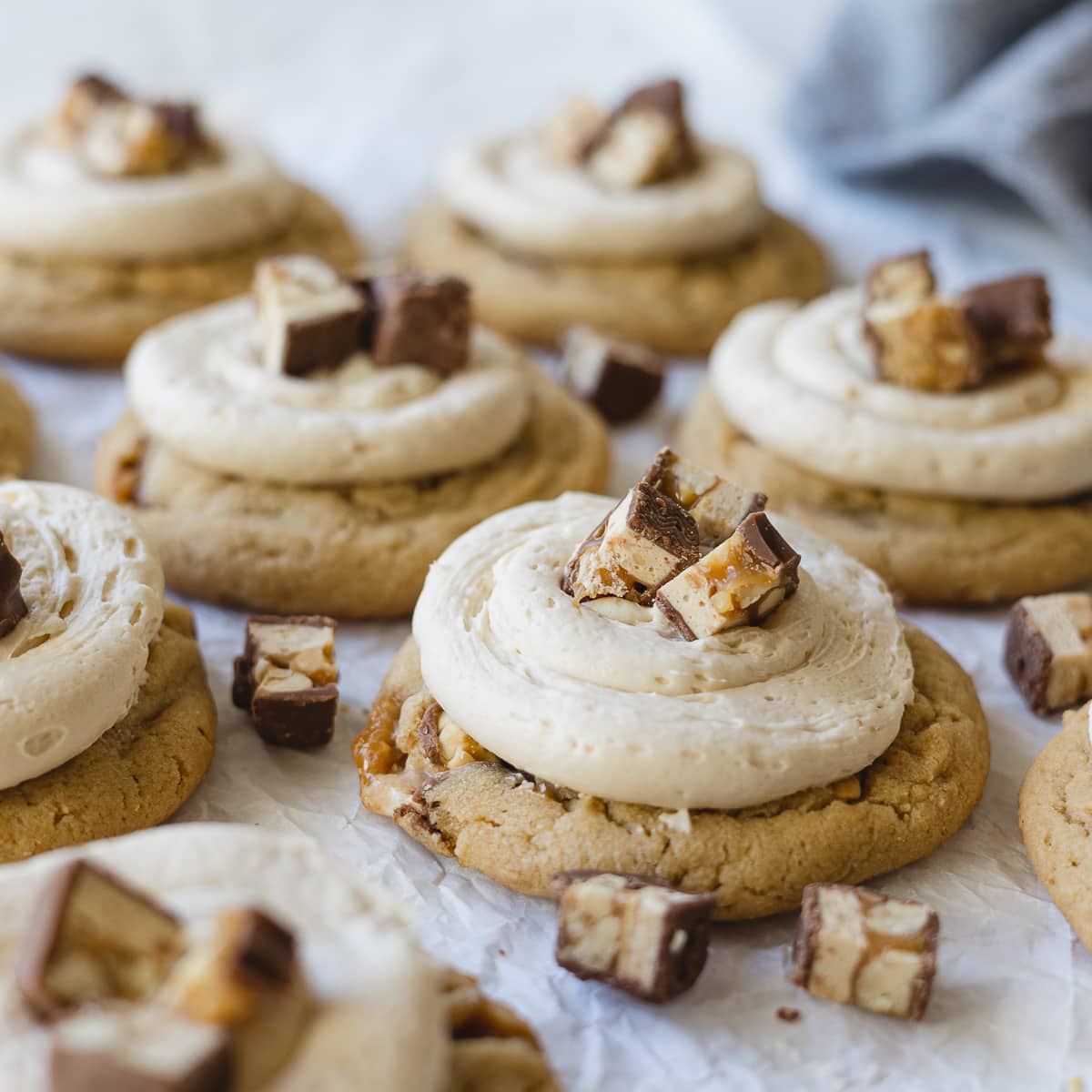Peanut butter cookies frosted with caramel buttercream and chopped Snickers bars.