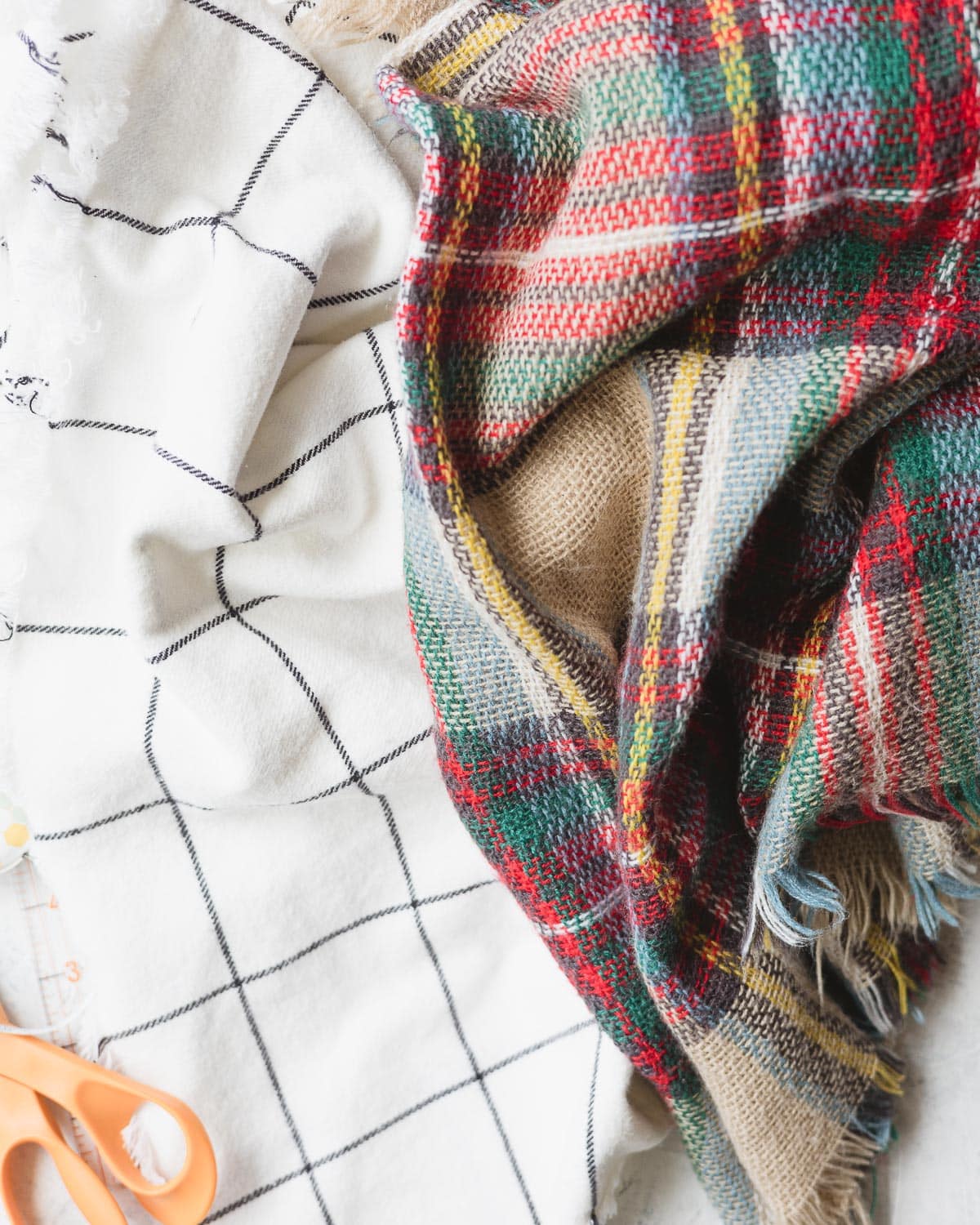 White fabric with black grid design and a colorful plaid blanket scarf.