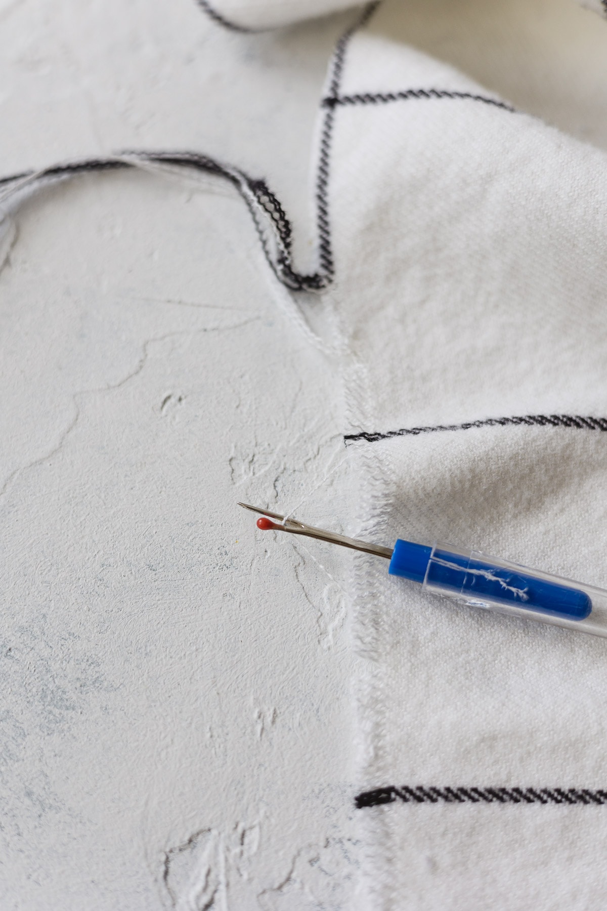 Using a small seam ripper to remove threads and fringe the edge of a DIY scarf.