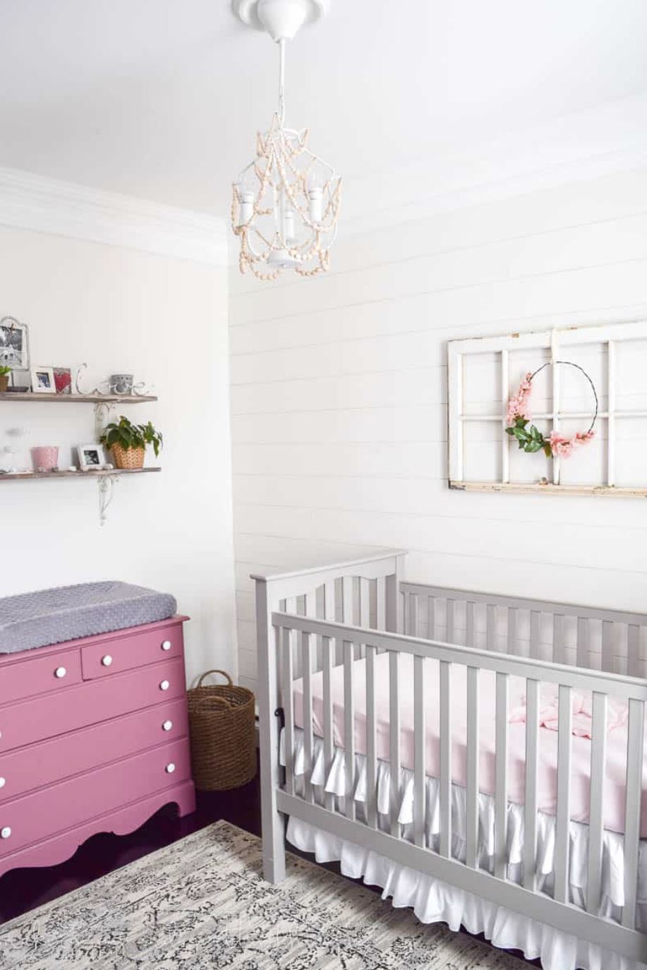 A farmhouse style baby girl's nursery with shiplap wall.