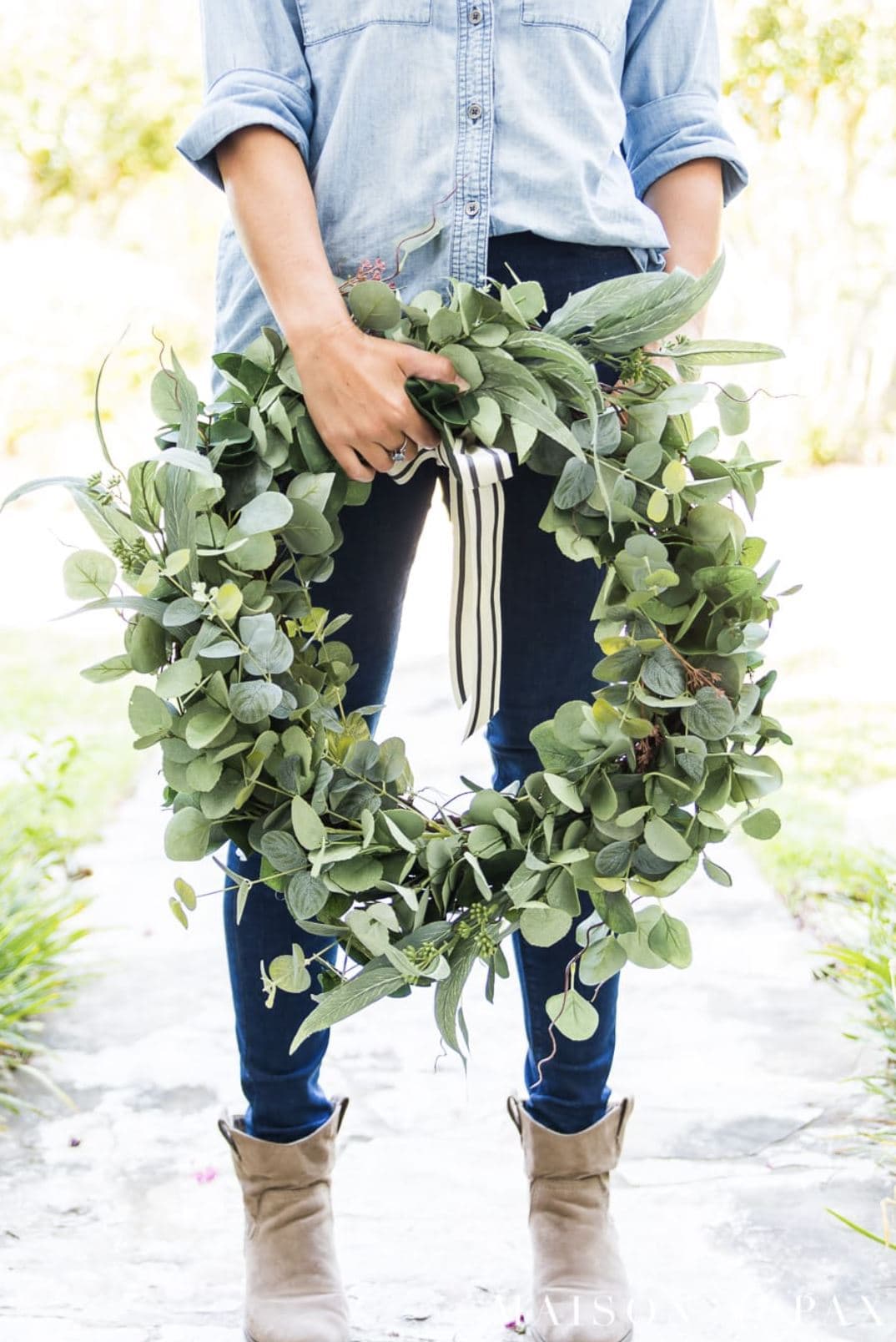 A woman holding a handmade eucalyptus wreath.
