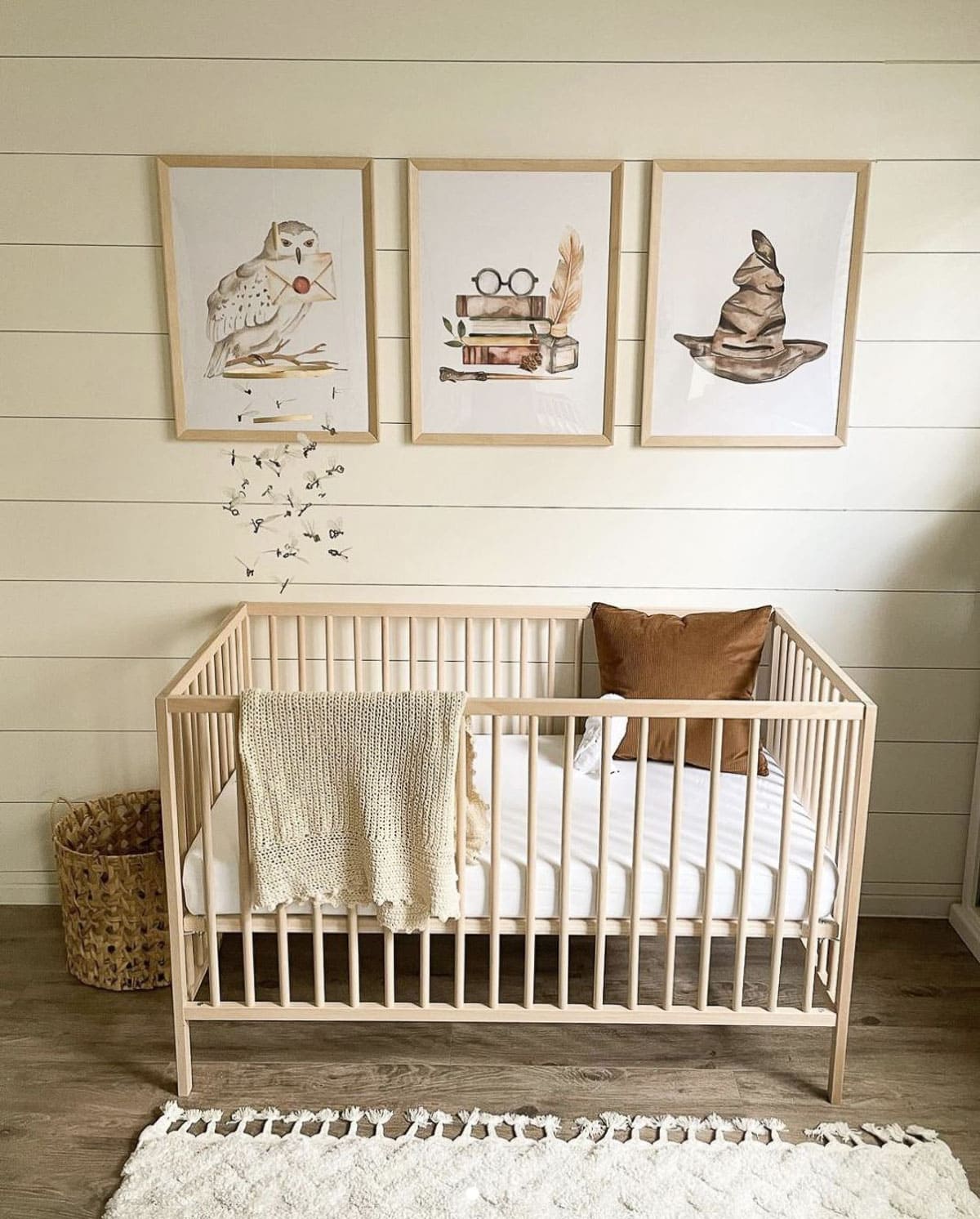 A Harry Potter inspired nursery with natural wood crib, keys mobile, and Harry Potter prints.