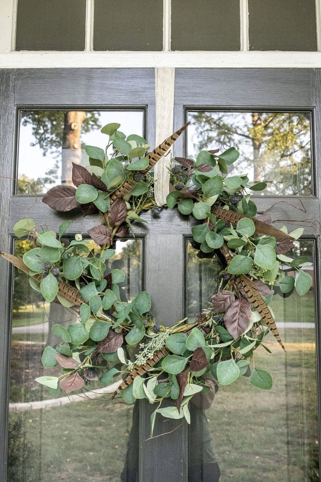 A fall wreath with feathers and eucalyptus.