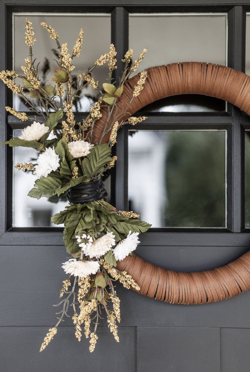 A wreath wrapped with leather and florals.
