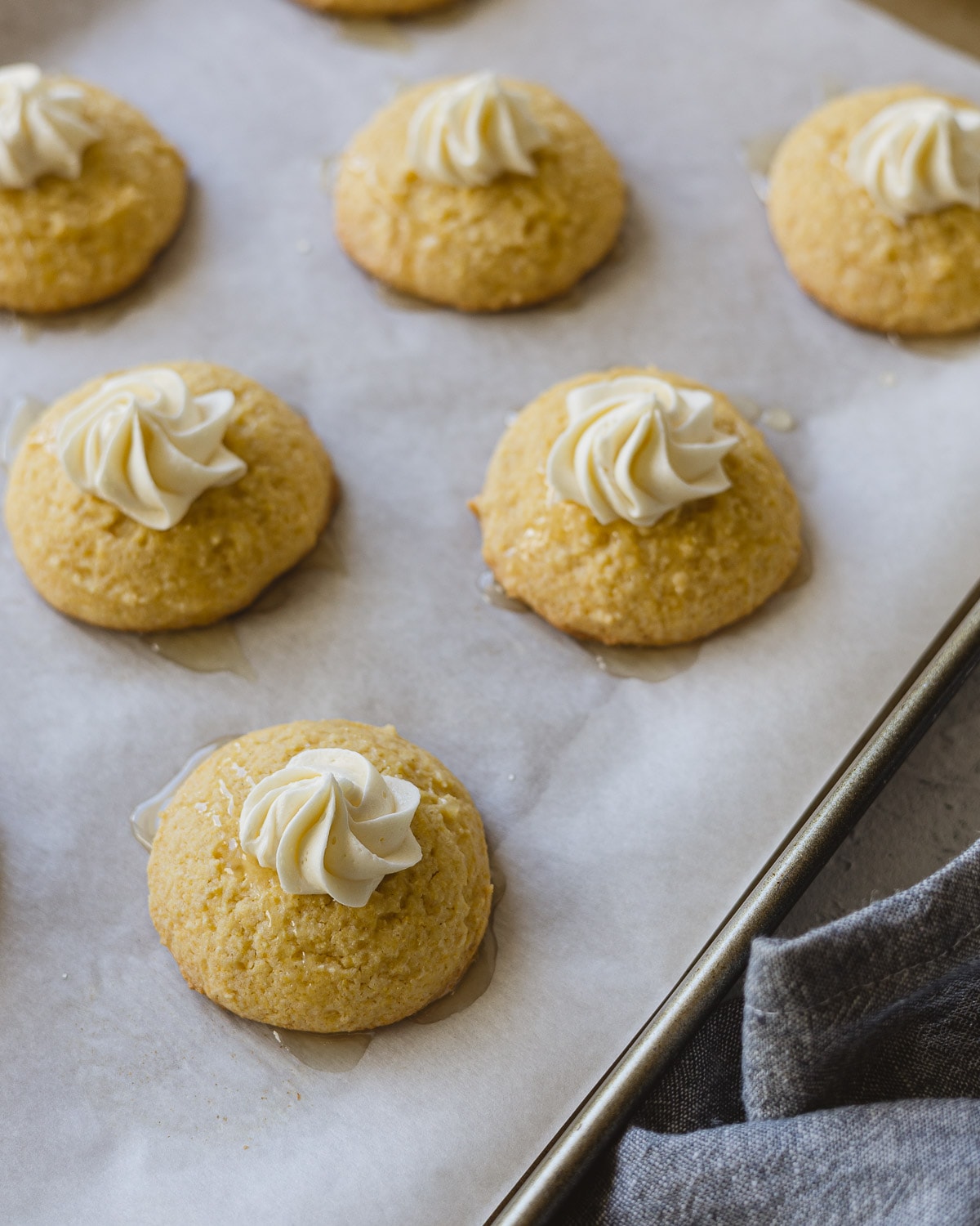 Cornbread Cookies with a piped honey buttercream star and drizzle of honey butter on a baking tray.