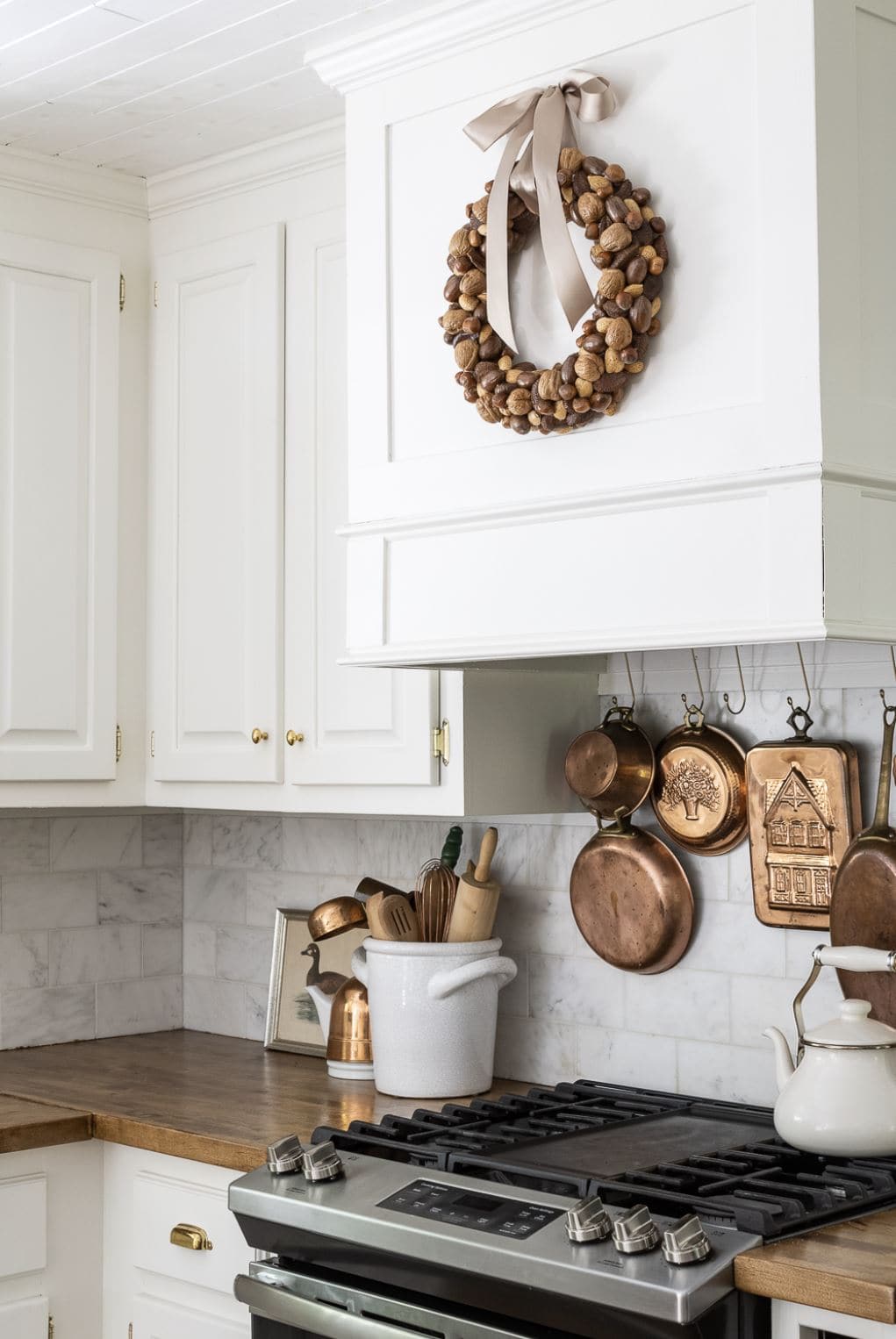 A harvest wreath made from a variety of mixed nuts hanging over the stove in a farmhouse kitchen.