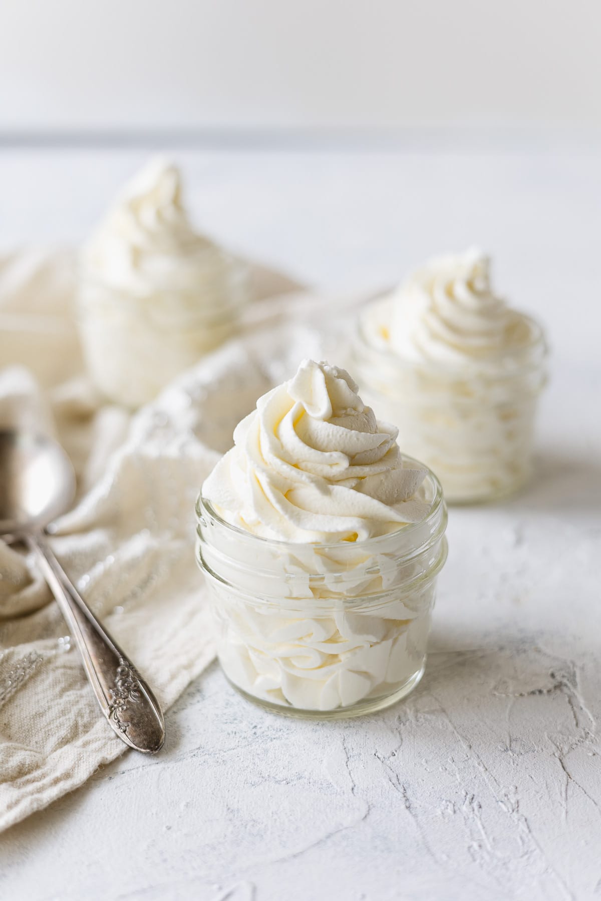 Mason jar filled with a swirl of piped whipped cream and a vintage spoon.