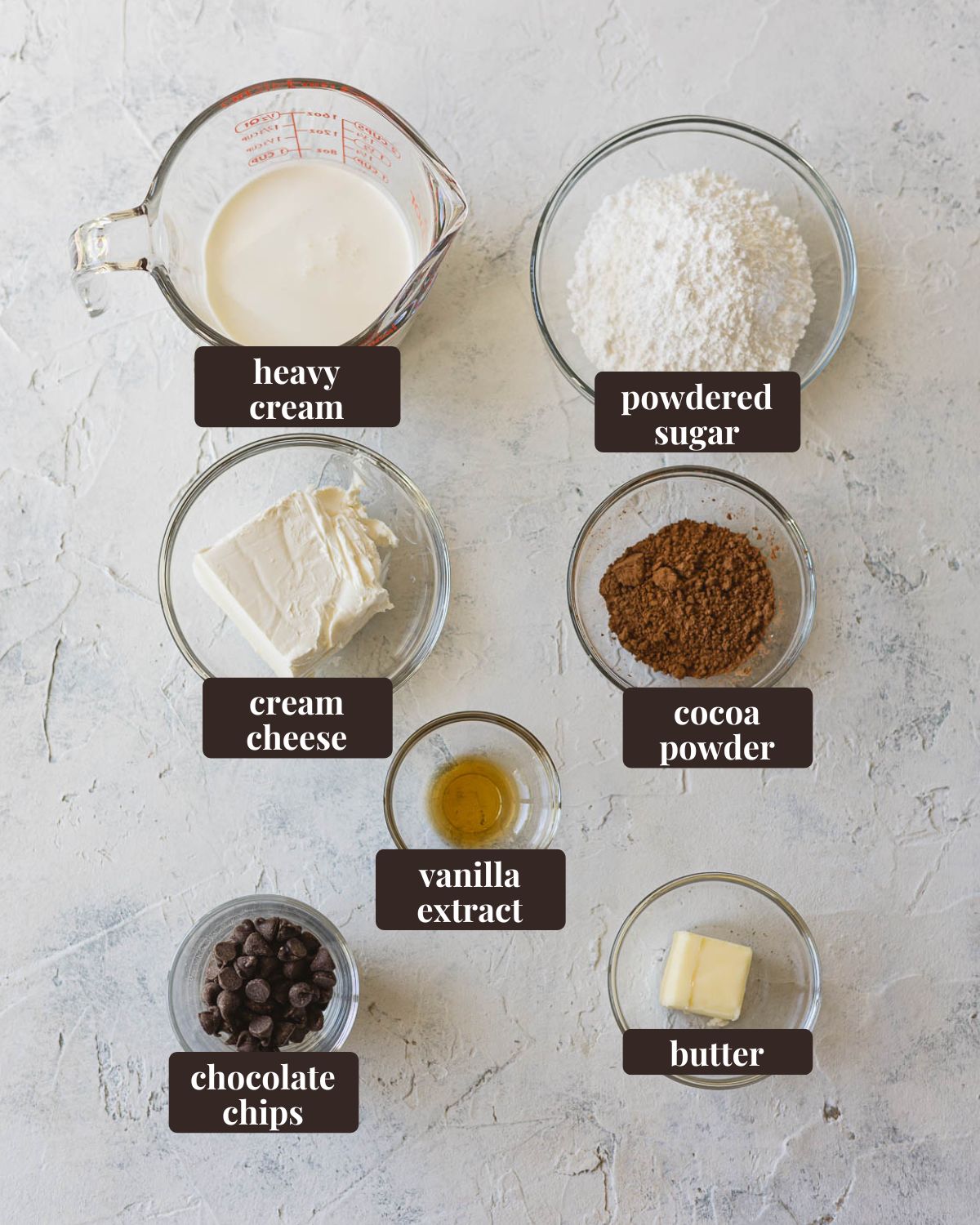 Labeled ingredients for no bake French Silk Pie filling: heavy cream, powdered sugar, cocoa powder, butter, chocolate chips, vanilla extract, and cream cheese.