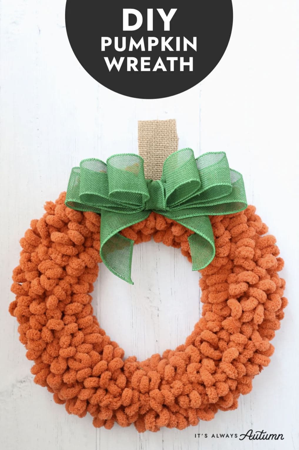 An orange loop yarn wreath with a large green bow with the words, "DIY Pumpkin Wreath."