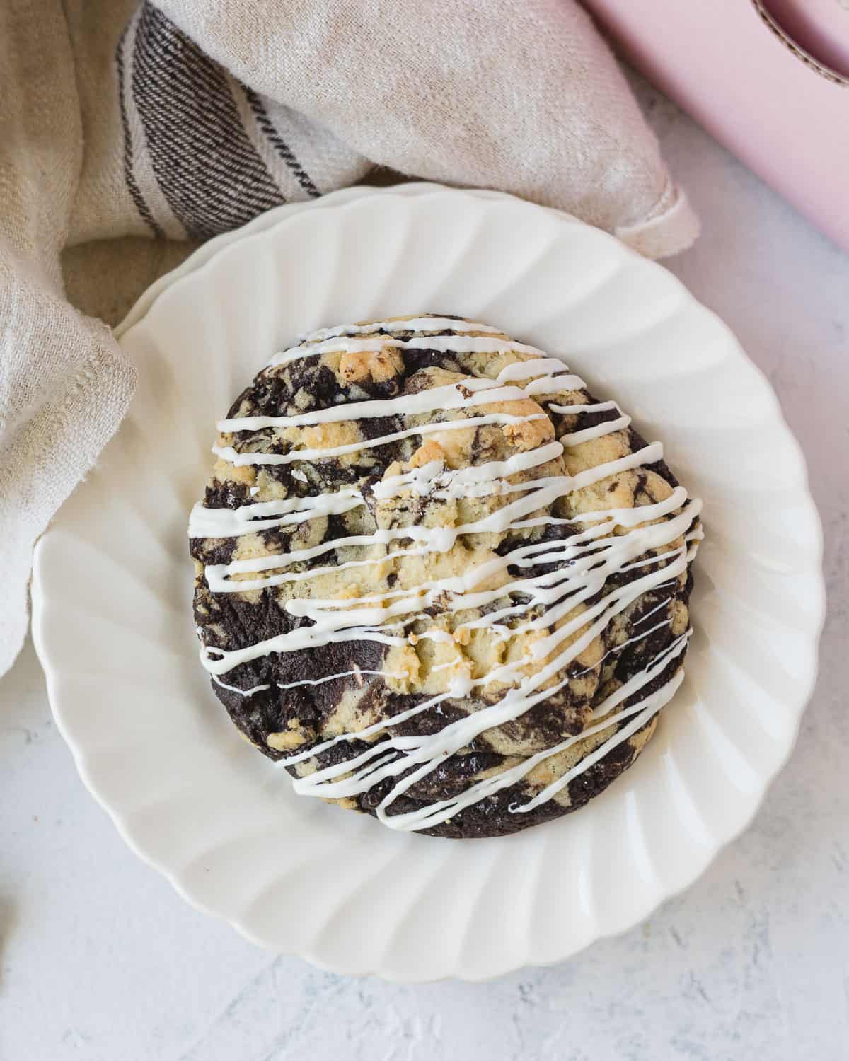 A Crumbl cookies and cream cookie with chocolate drizzle on a plate.