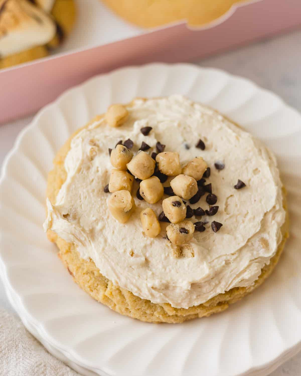 A Crumbl Chocolate Chip Cookie Dough cookie with frosting and mini scoops of cookie dough on top.