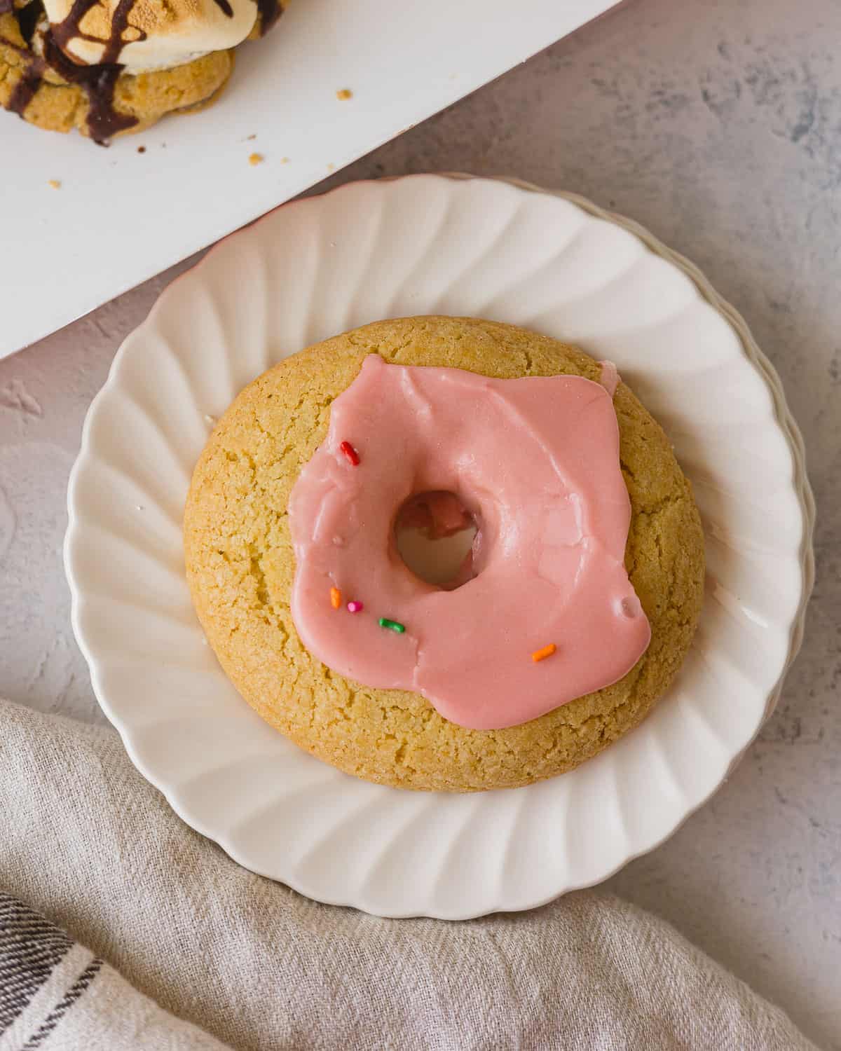 A Crumbl Pink Doughnut with pink glaze and sprinkles.