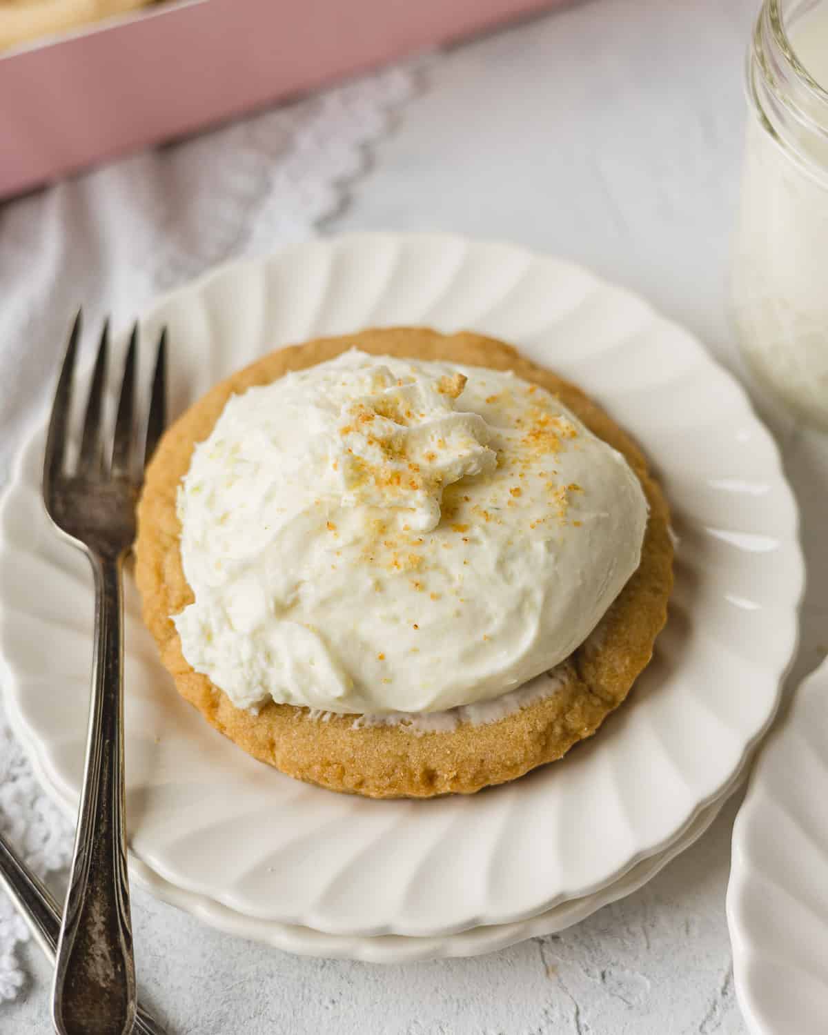 Crumbl Key Lime Pie cookie with scoop of key lime pie filling and whipped cream on a plate with a small fork.