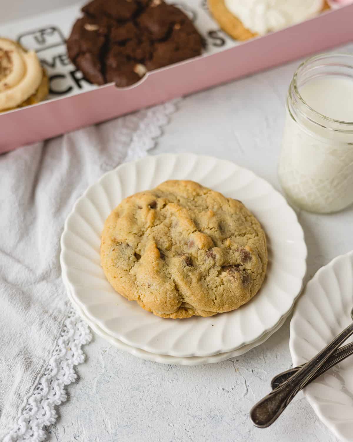 Crumbl Milk Chocolate Chip on a stack of small plates with a glass of milk.