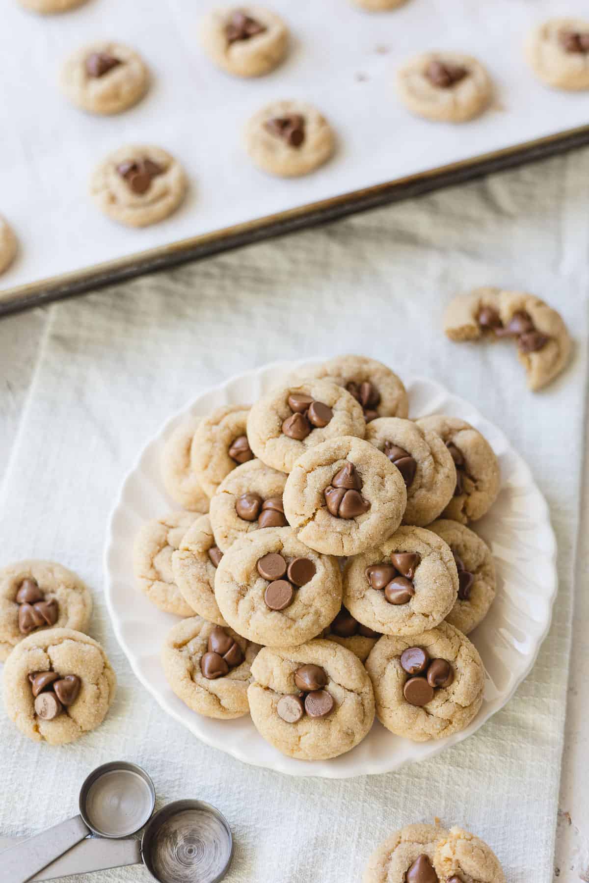 A small dessert plate piled with mini peanut butter blossom cookies with milk chocolate chips pressed into the middles.