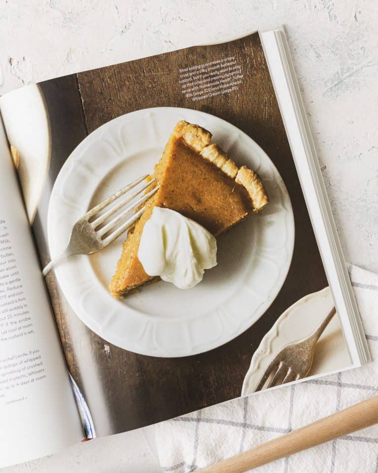 An interior photo from the "BraveTart" cookbook showing a slice of plated pumpkin pie with whipped cream on top.