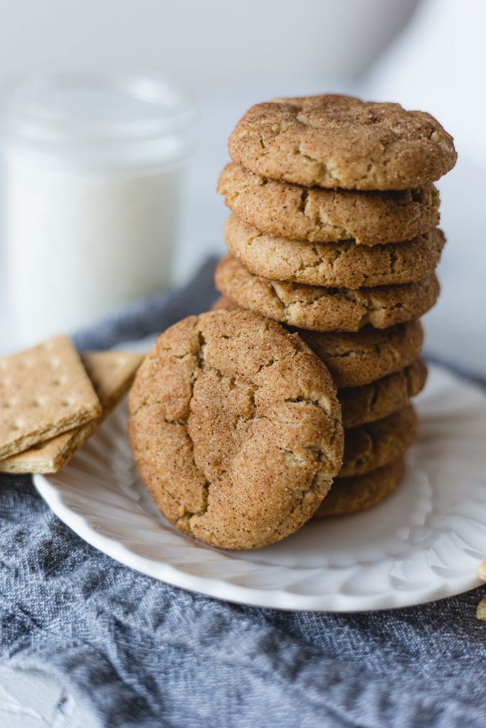 A stack of graham cracker cookies on a white plate with blue napkin underneath.