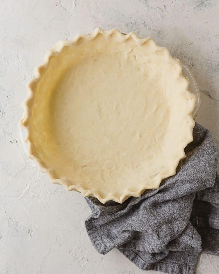 An unbaked pie crust with crimped edges fitted into a pie plate.