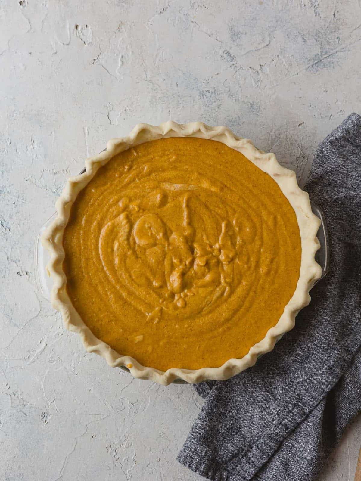 Pumpkin pie filling poured into an unbaked pie crust.