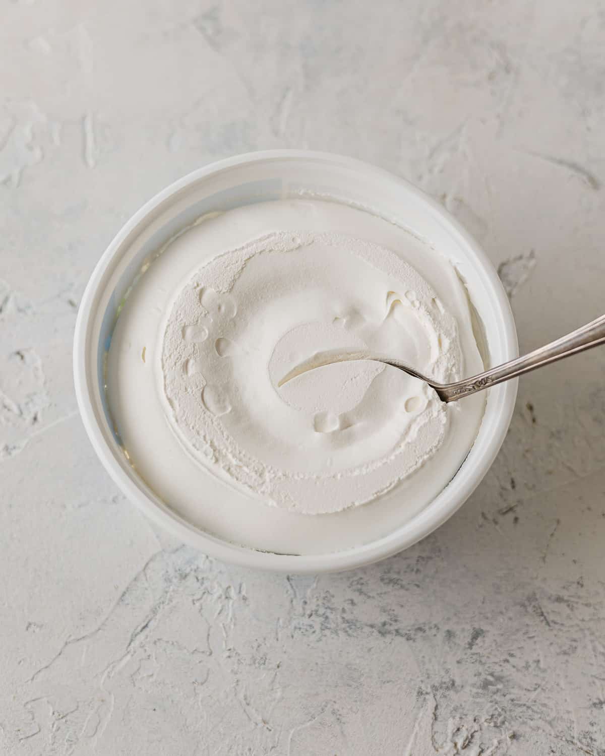 An open container of whipped topping with a spoon in it.