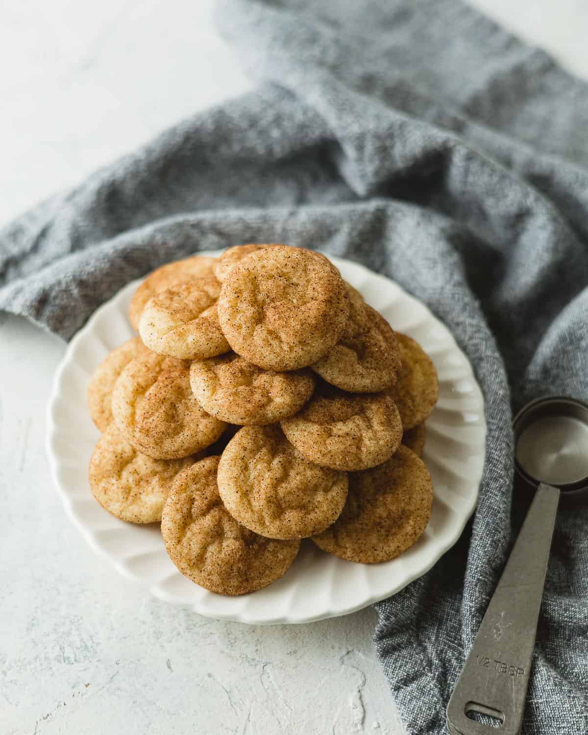 A small plate of snickerdoodle cookies and metal measuring spoons.