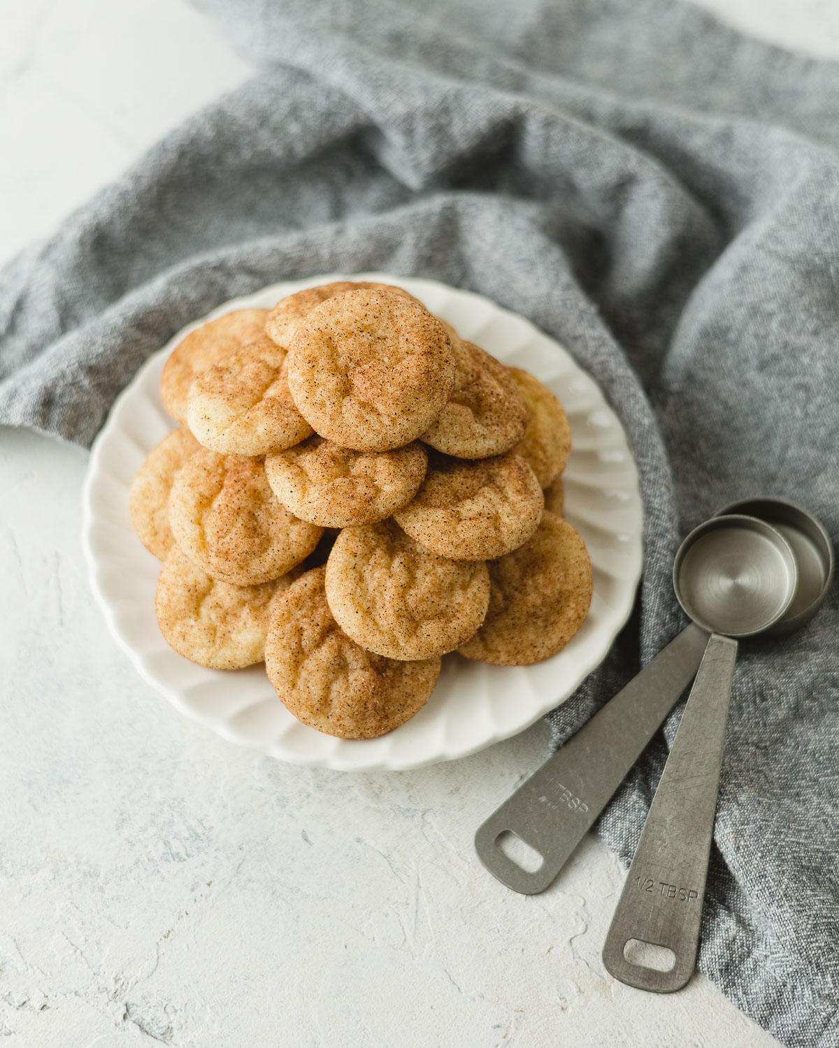 A small plate of mini snickerdoodles and two metal measuring spoons.
