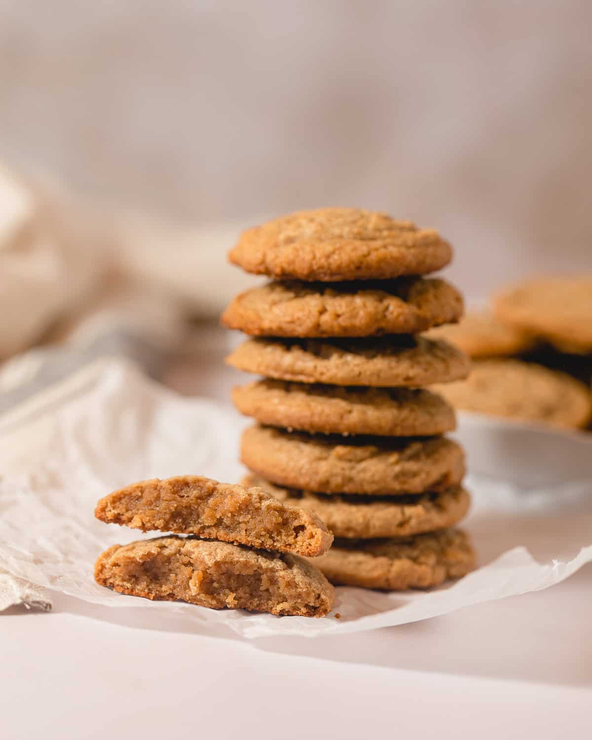 A large stack of peanut butter cookies with one broken in half with the halves stacked.