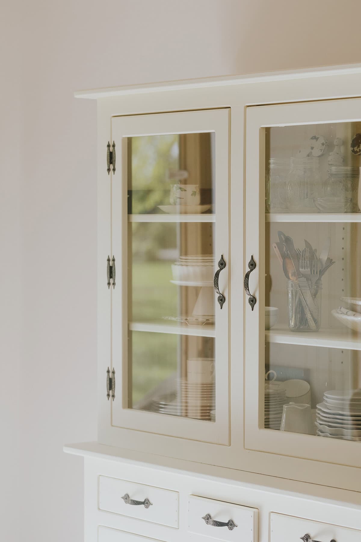 A hutch with glass doors and flatware and dishes inside.