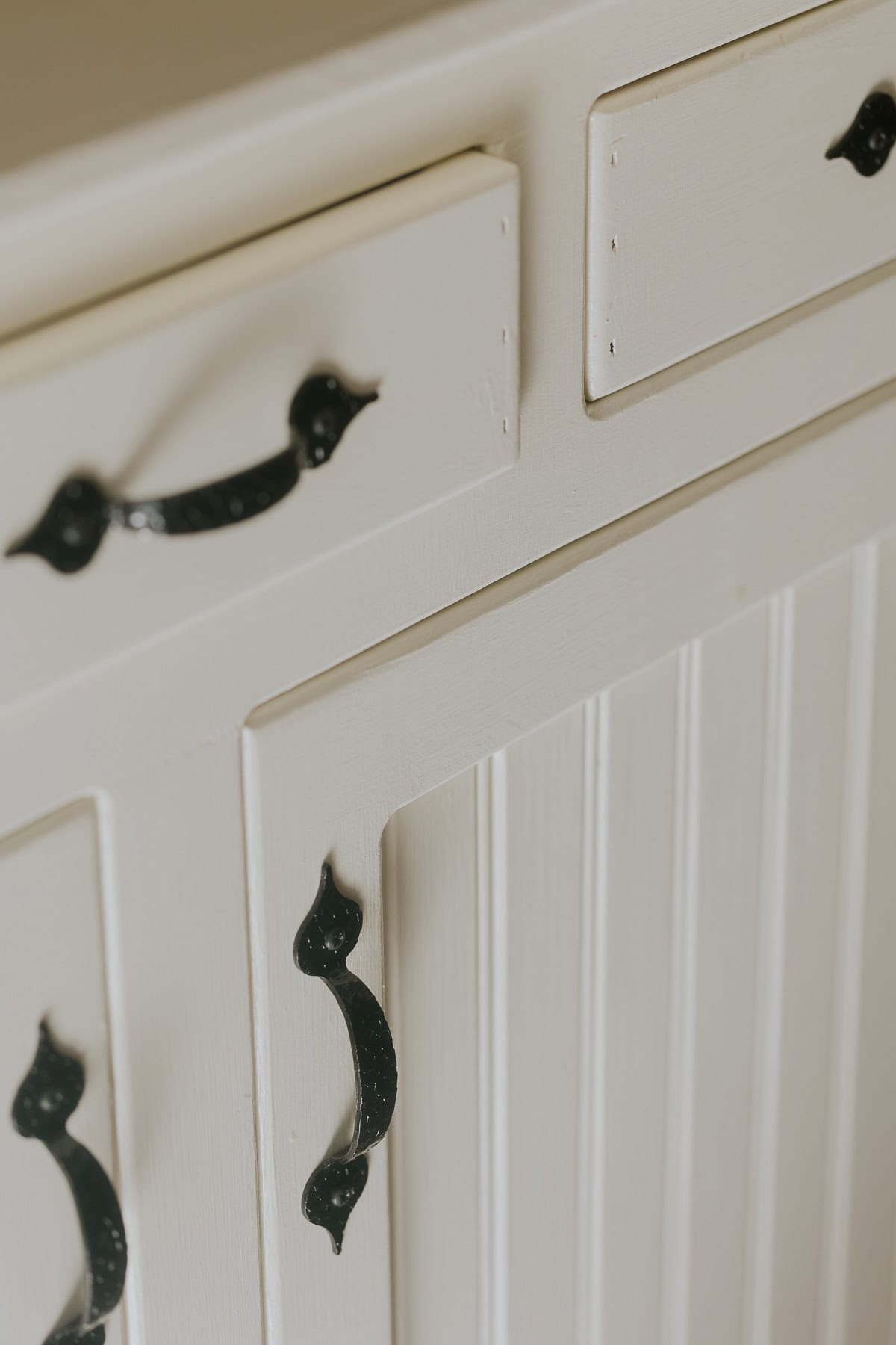 A bead board cupboard door on a white painted hutch.