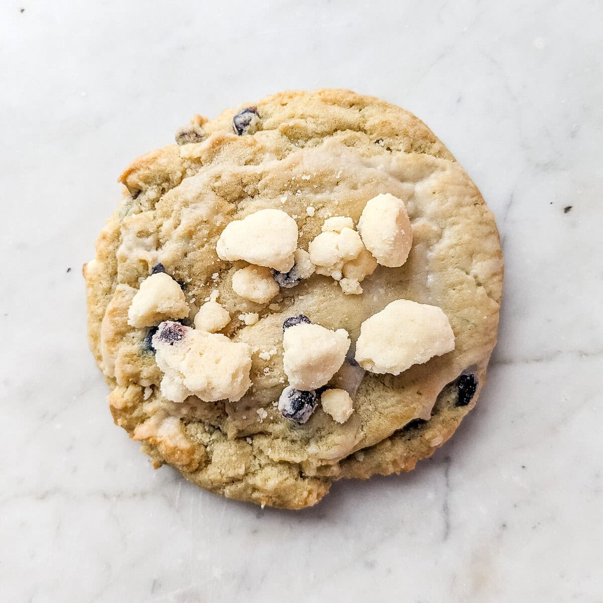 A Crumbl blueberry muffin cookie with streusel chunks on top.