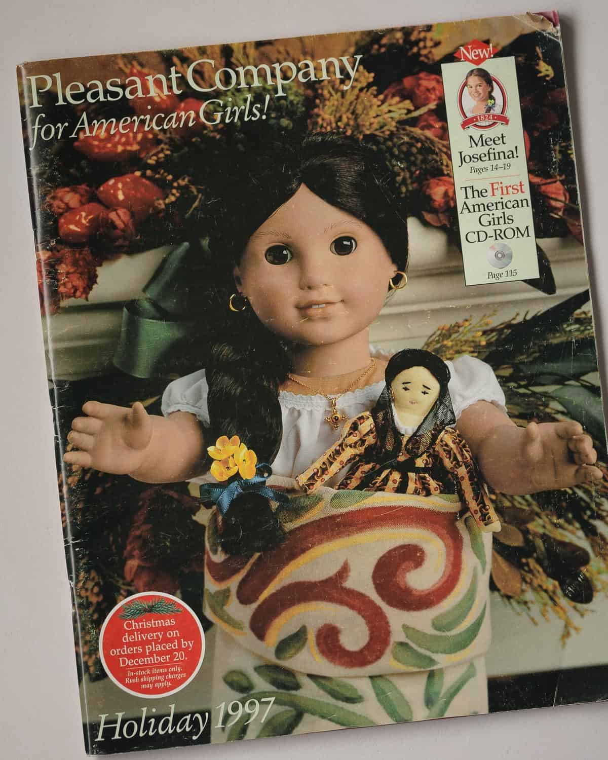 The cover of a Pleasant Company Holiday 1997 catalog with a Josefina doll and her mini doll tucked into a holiday stocking.
